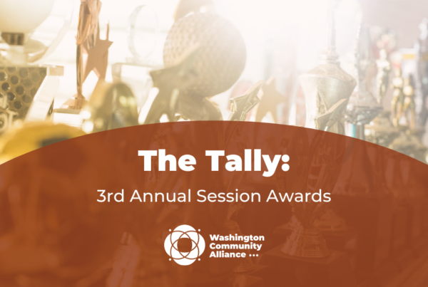 Out of focus photo of several gold awards in the background with a rust colored arch overlayed and in white text reads "The Tally: 3rd Annual Session Awards" with the Washington Community Alliance logo.